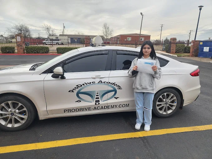 Un estudiante de ProDrive Academy junto a uno de los autos de la escuela
