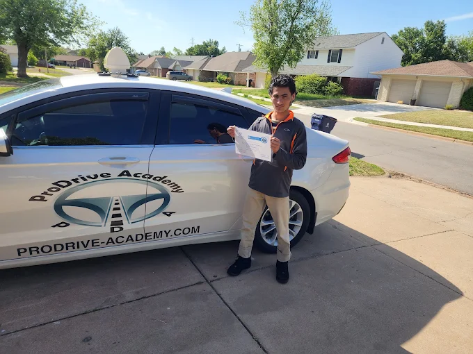 Un estudiante de ProDrive Academy junto a uno de los autos de la escuela