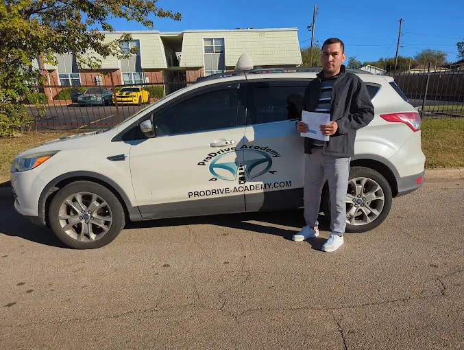 Un estudiante de ProDrive Academy junto a uno de los autos de la escuela